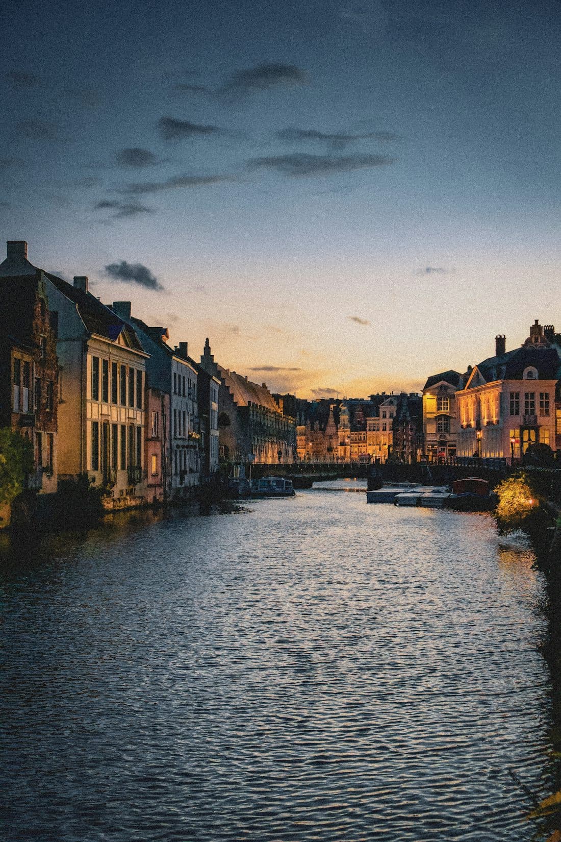 Ghent canal at dusk, stepped-gable houses glowing along the water